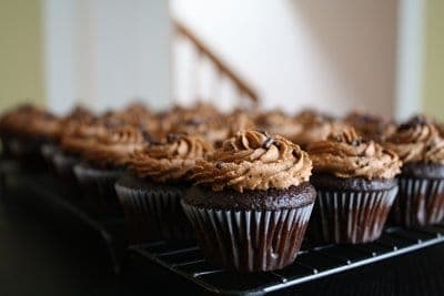 Chocolate cupcakes with chocolate frosting on a metal baking rack