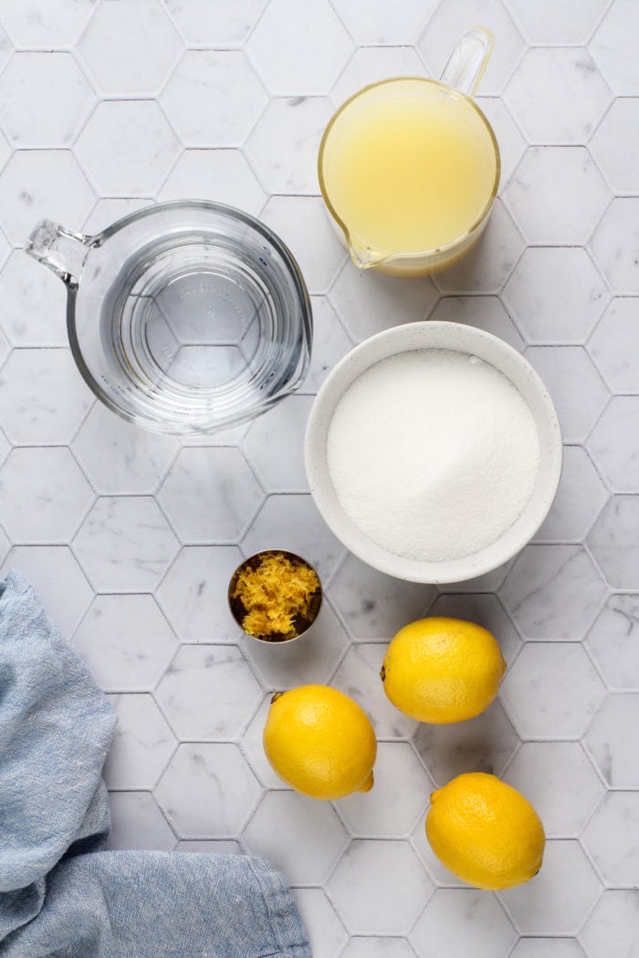 Ingredients for lemon sorbet arranged on a white tile countertop.