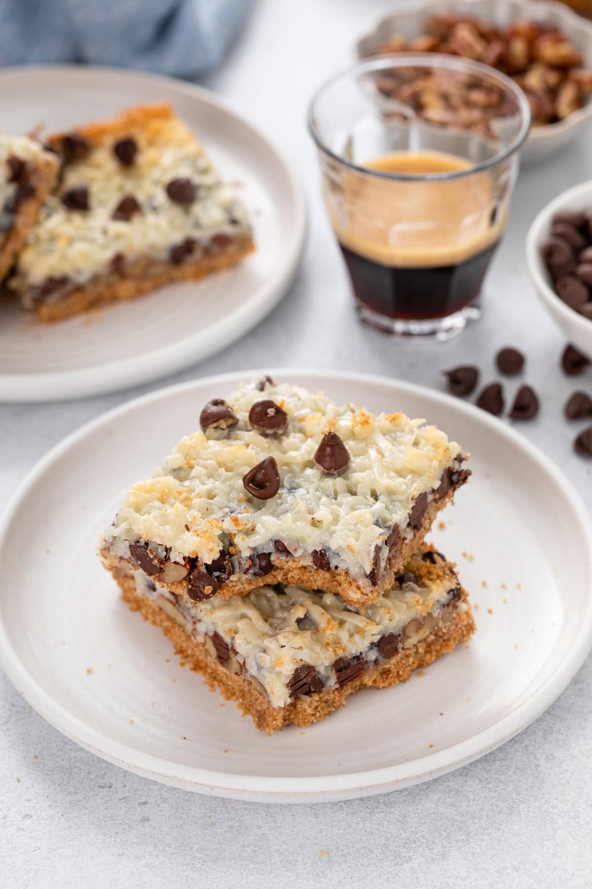Two magic bars stacked on a white plate, with a bite taken from the corner of the top bar.