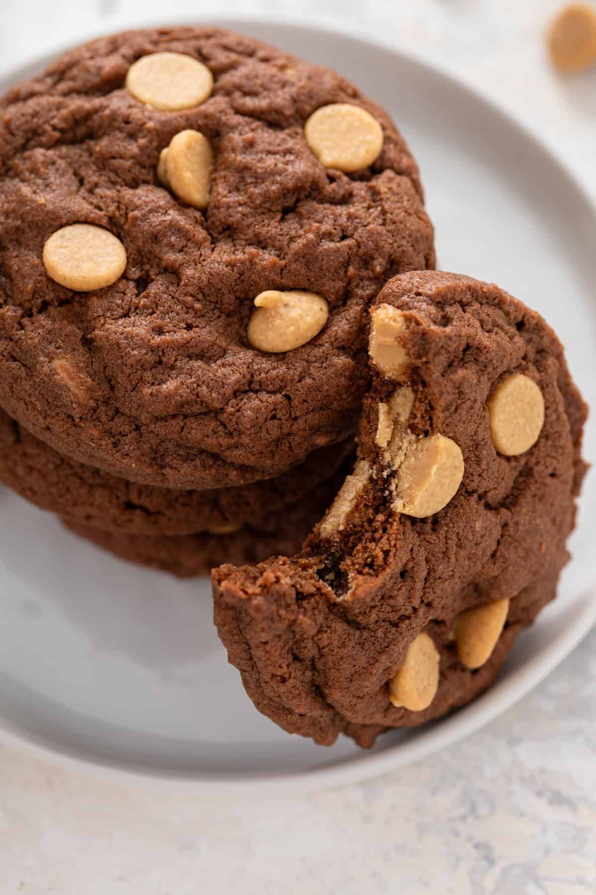 Chocolate peanut butter cookies in a white plate with a bite taken out of one of them.