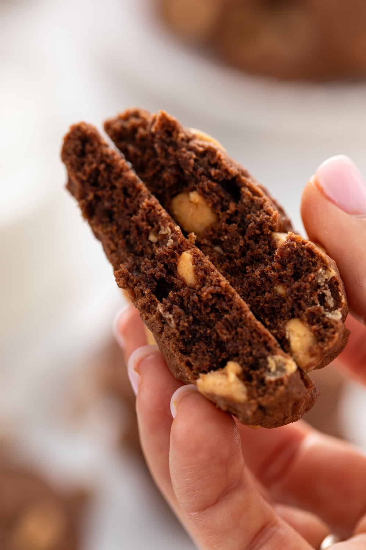 Hand holding a chocolate peanut butter cookie broken in half.