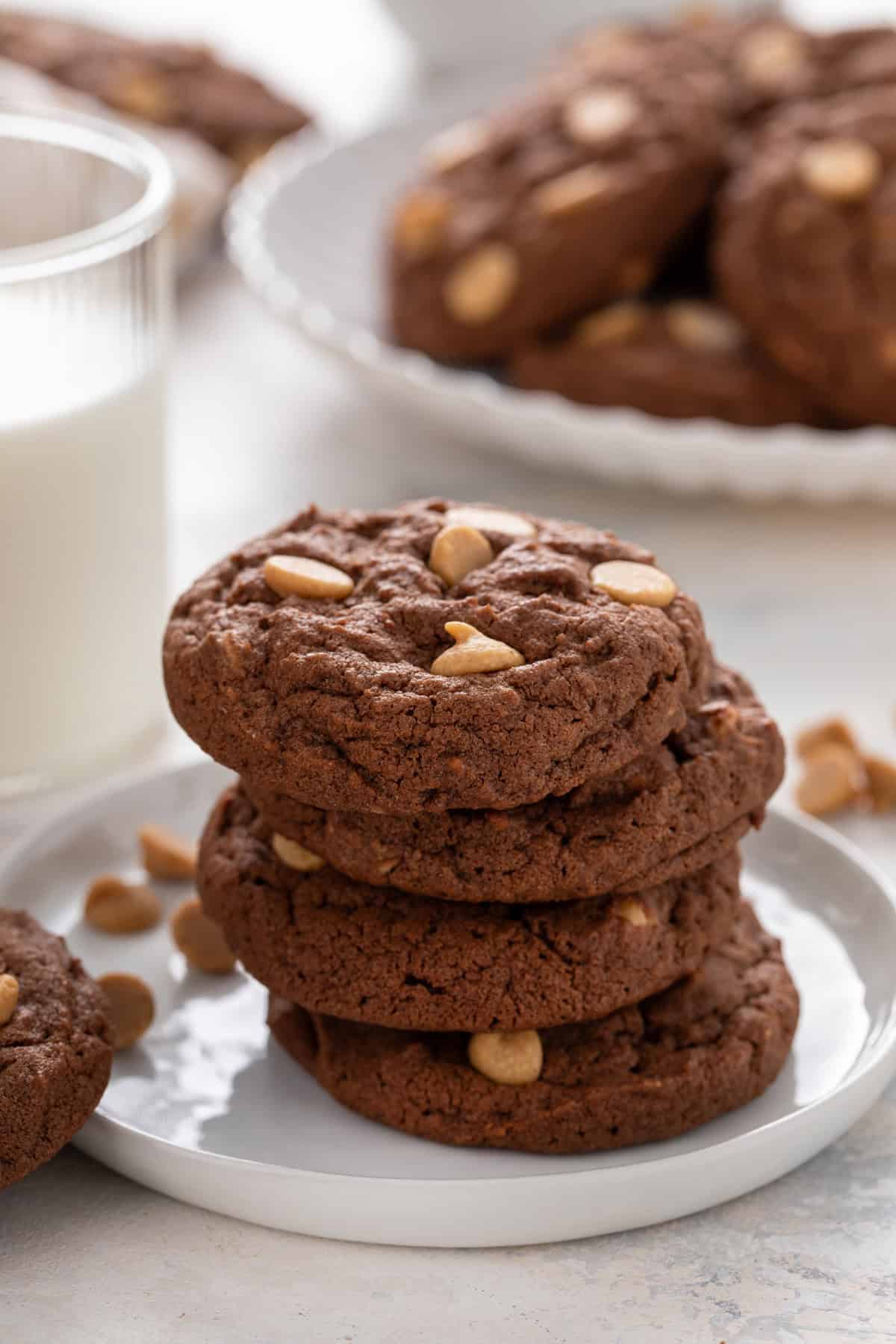 Four chocolate peanut butter cookies stacked on a white plate.