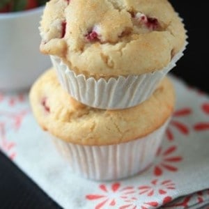 Two strawberry lemon muffins stacked on top of each other on a white and red decorated napkin
