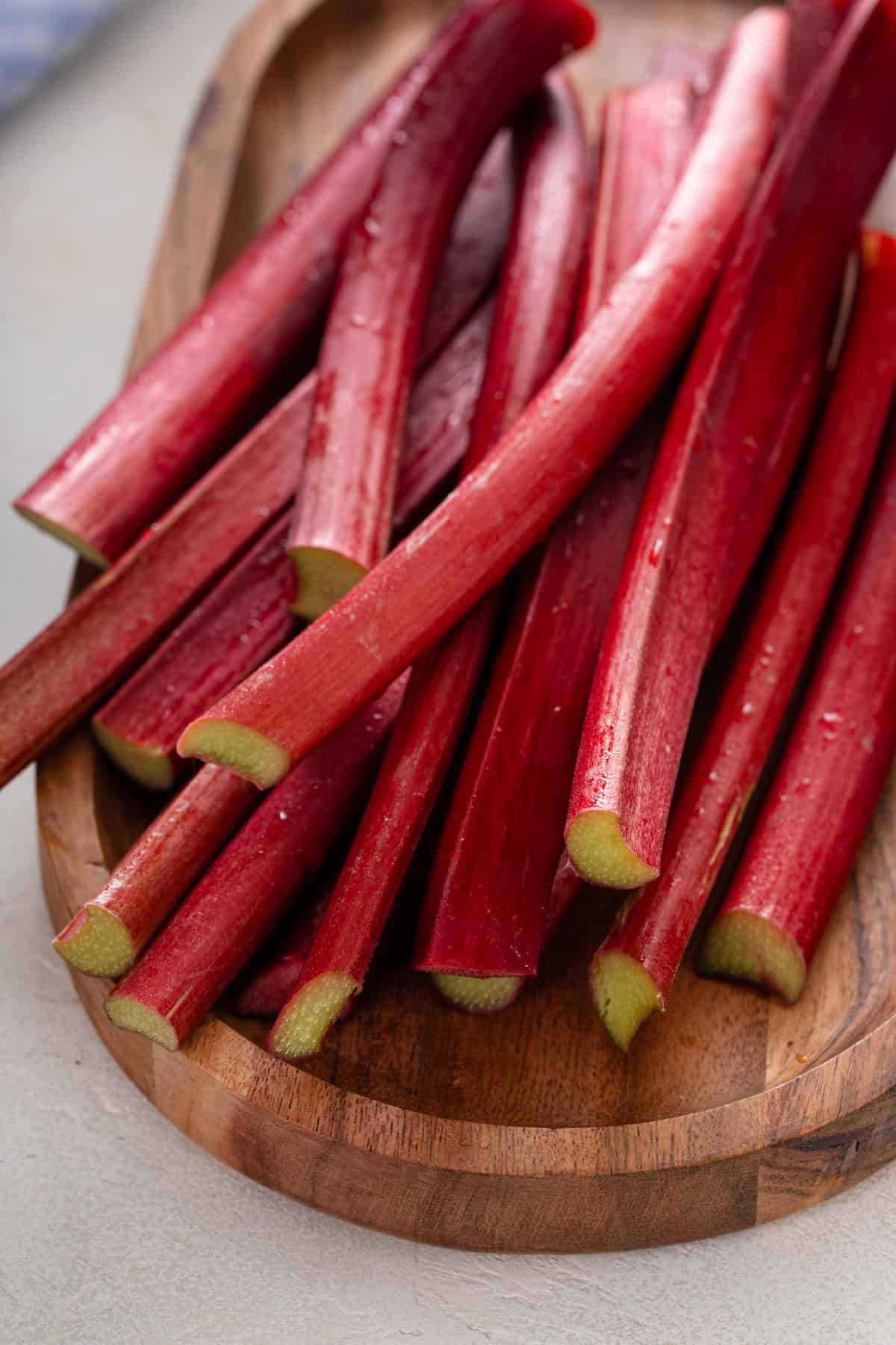 Stalks of fresh rhubarb on a wooden board.