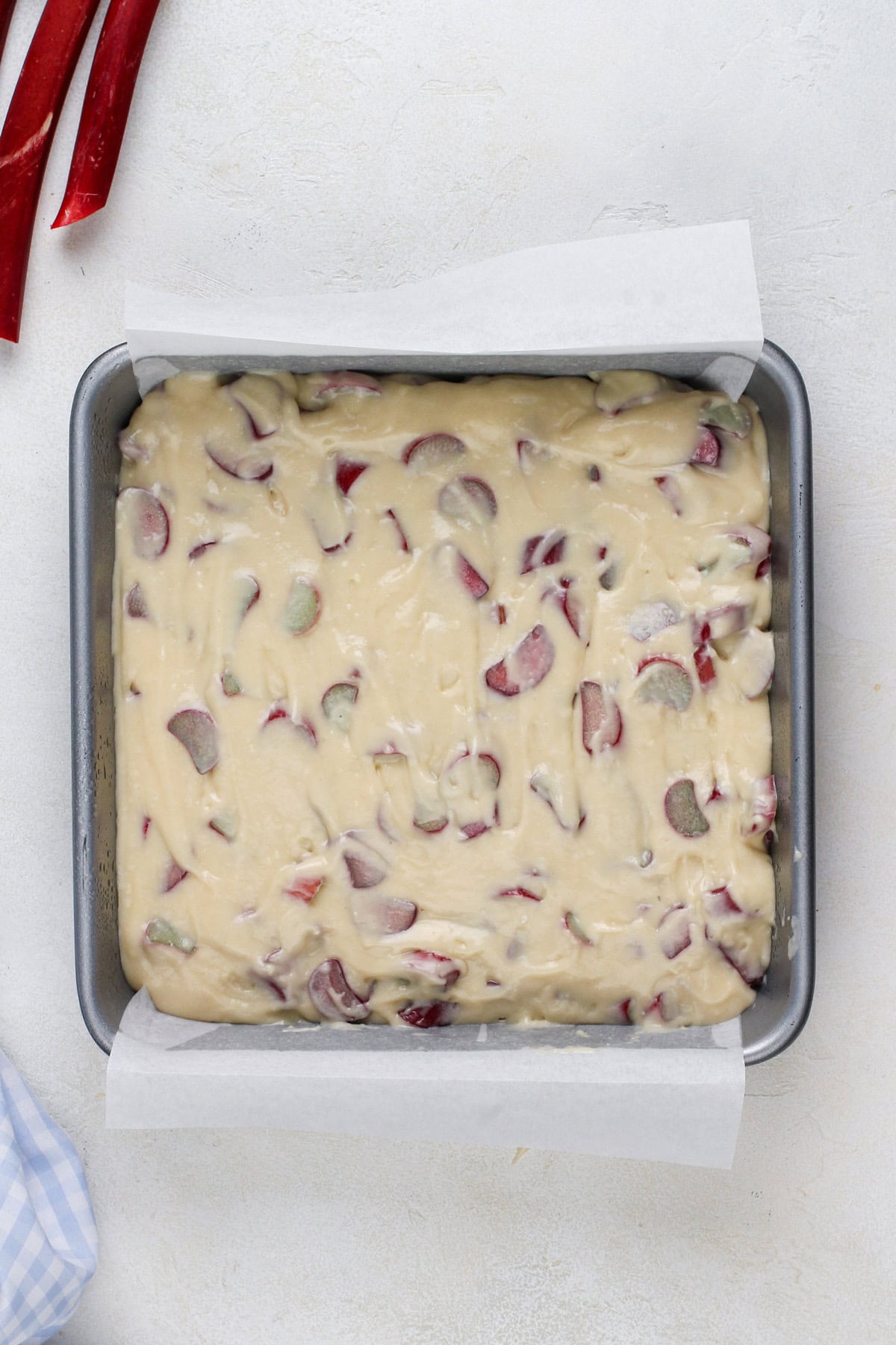 Rhubarb cake batter spread into a cake pan.