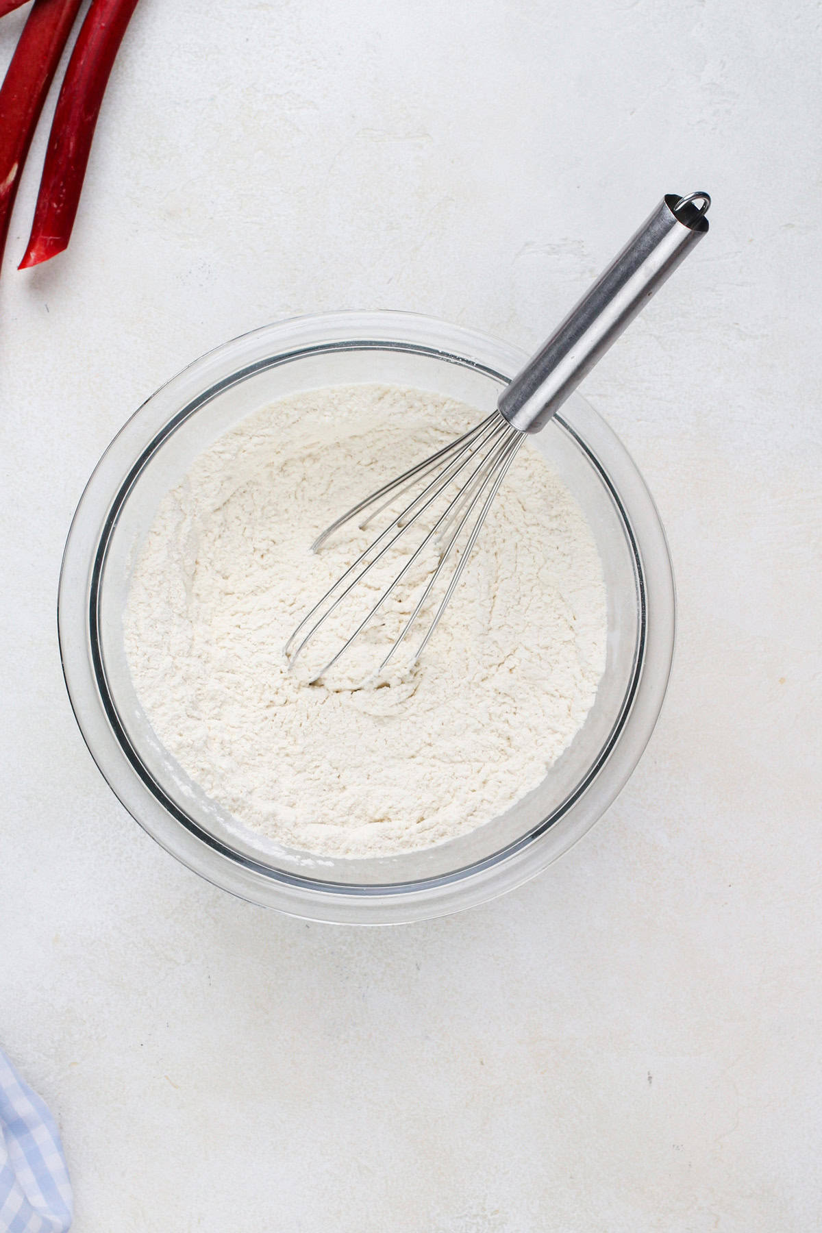 Dry cake ingredients whisked in a glass bowl.