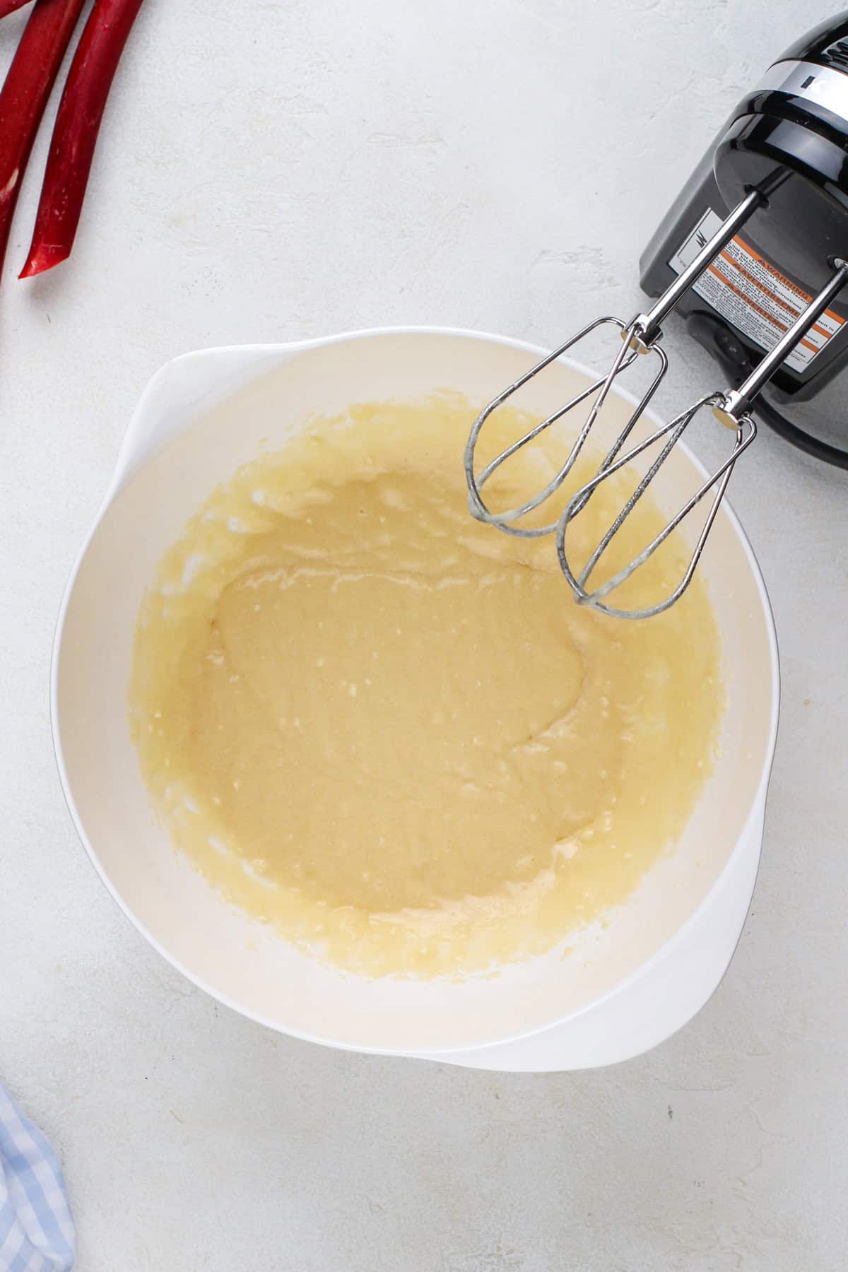 Wet ingredients for rhubarb cake mixed in a white bowl.