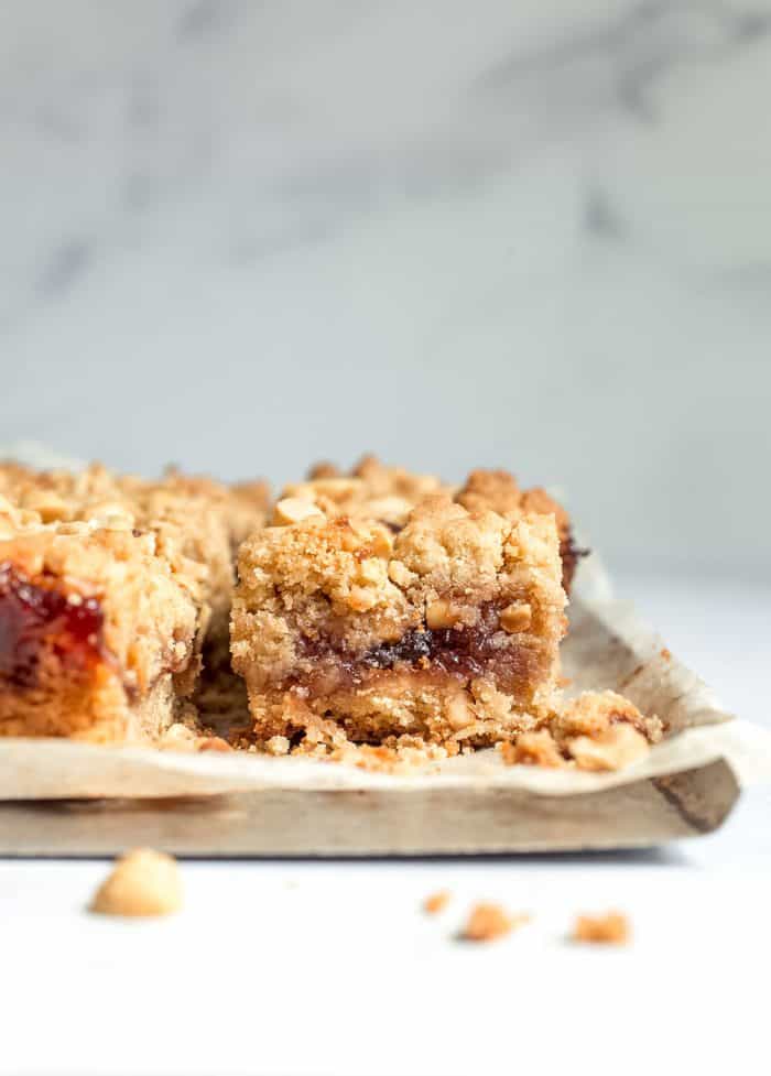 Side view of sliced peanut butter and jelly bars on a parchment-lined cookie sheet