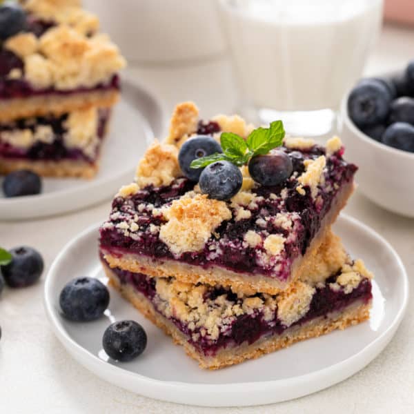 Two blueberry crumb bars stacked on a white plate.