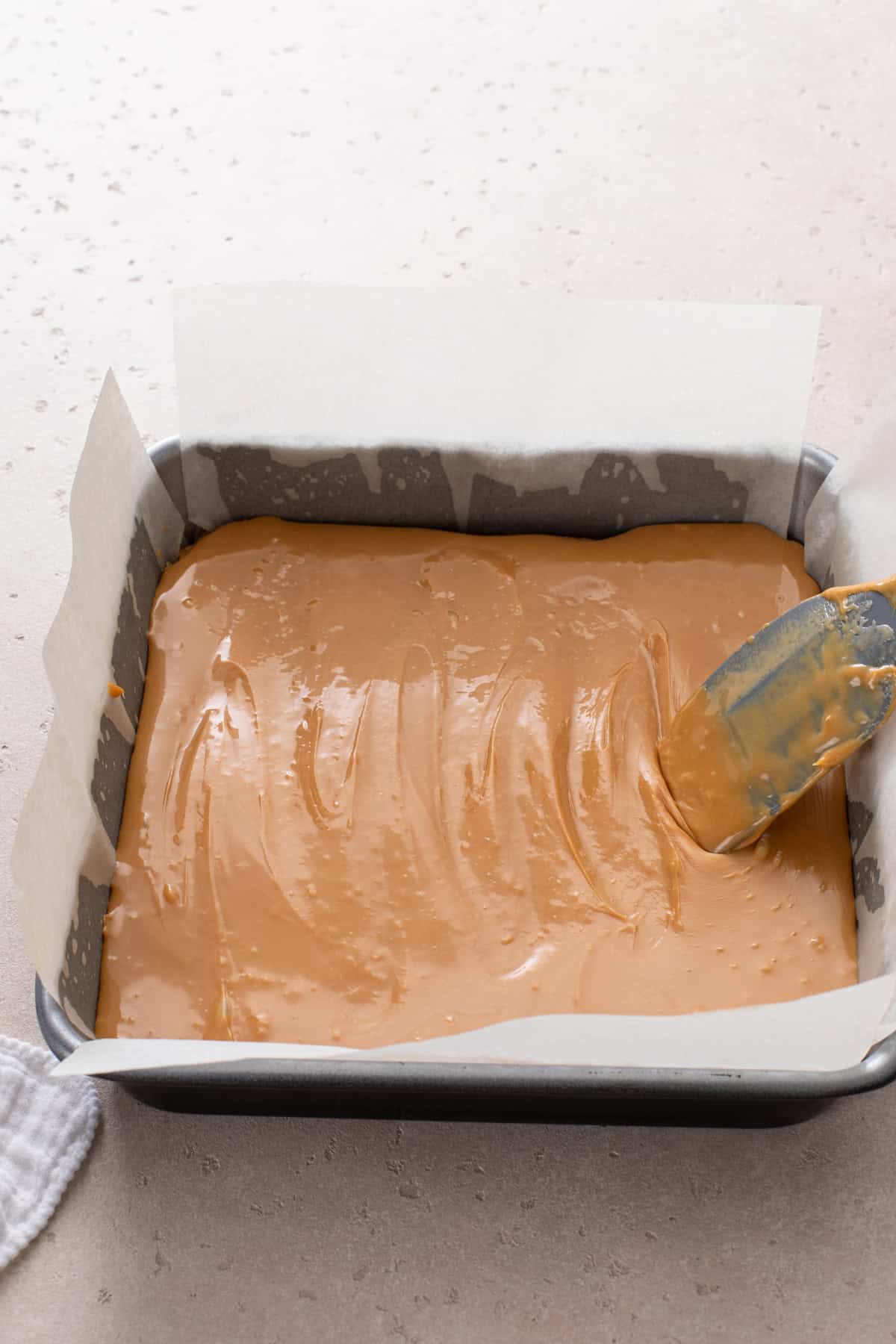 Caramel spread over shortbread in a baking pan.