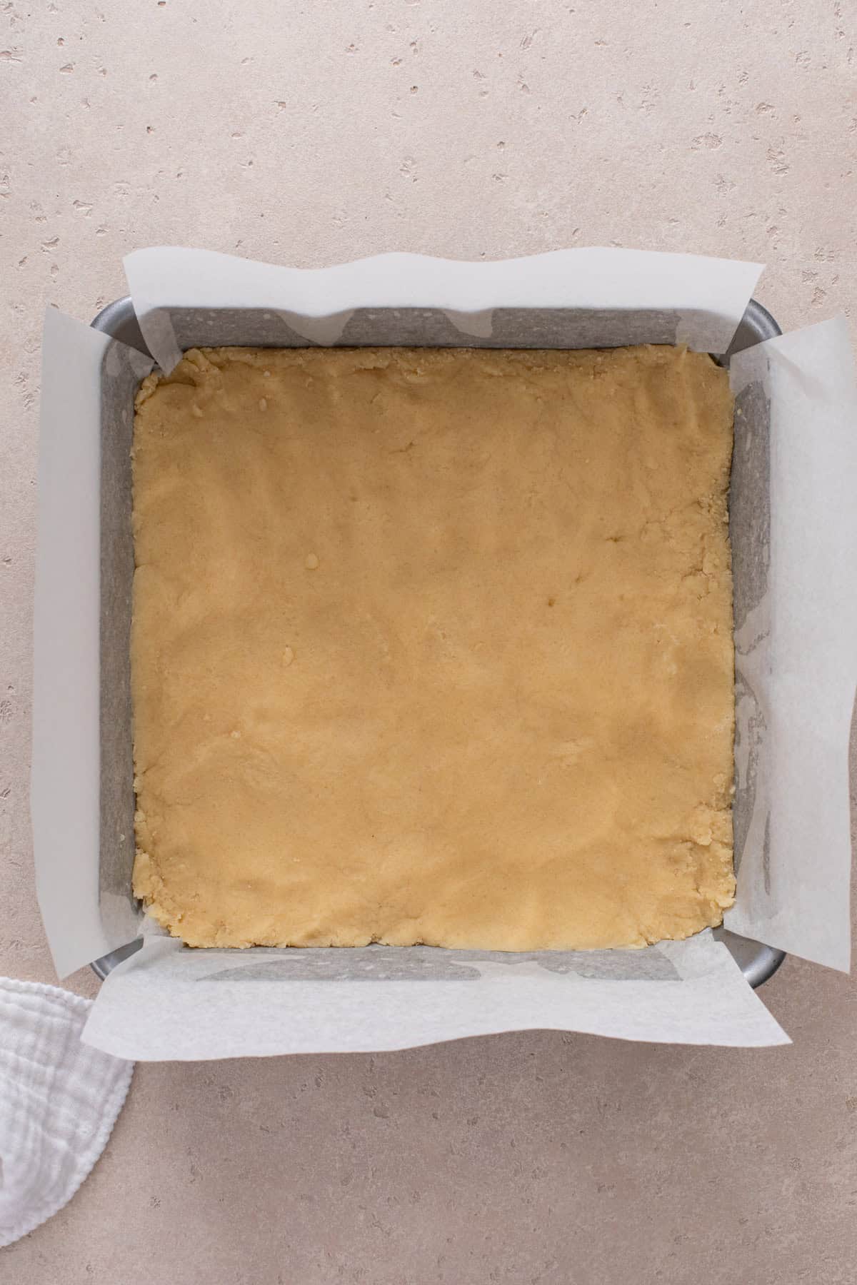 Shortbread dough pressed into the bottom of a baking pan, ready to go in the oven.