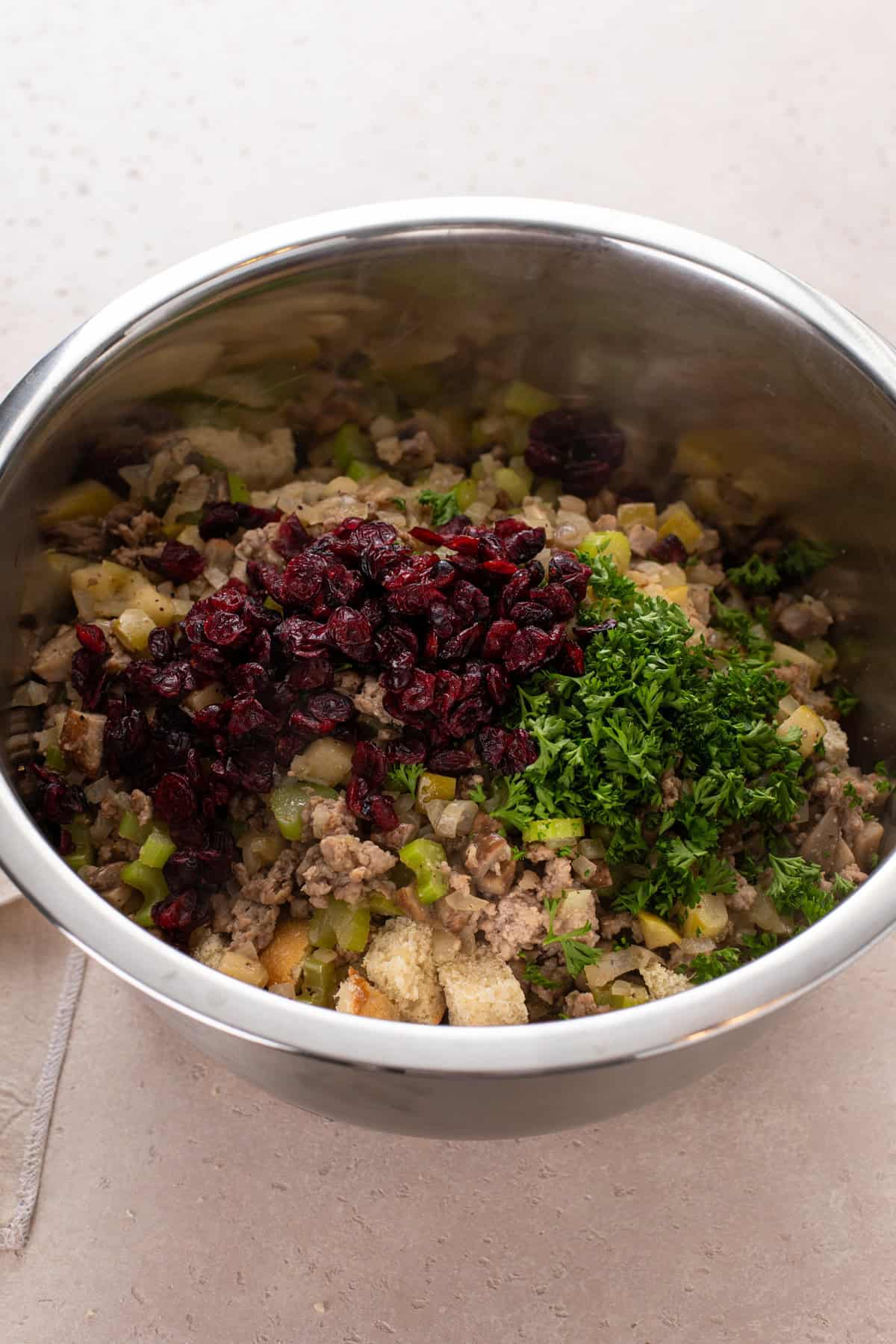 Ingredients for sausage and cranberry stuffing in a large bowl.
