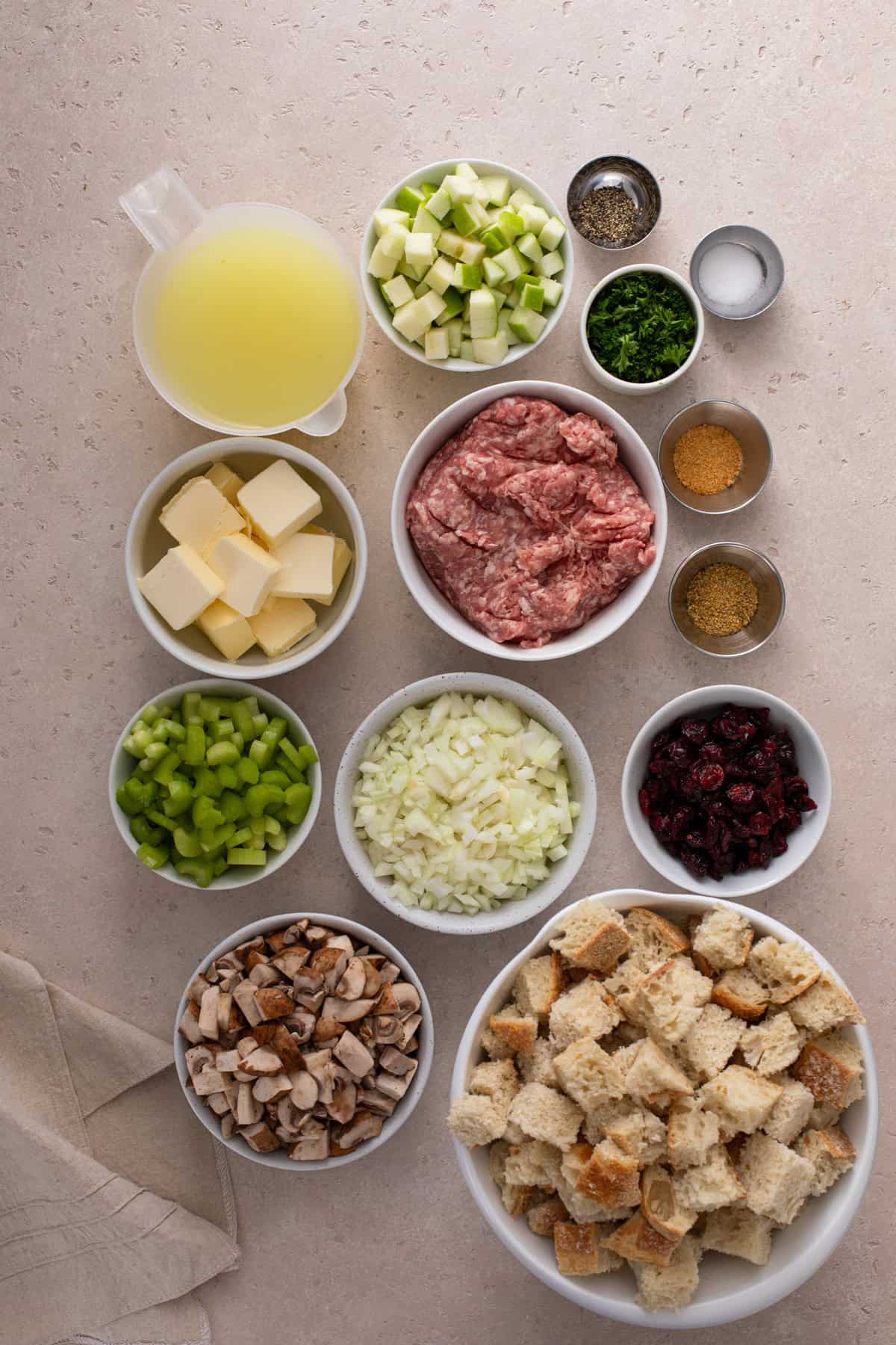 Ingredients for sausage and cranberry stuffing arranged on a countertop.
