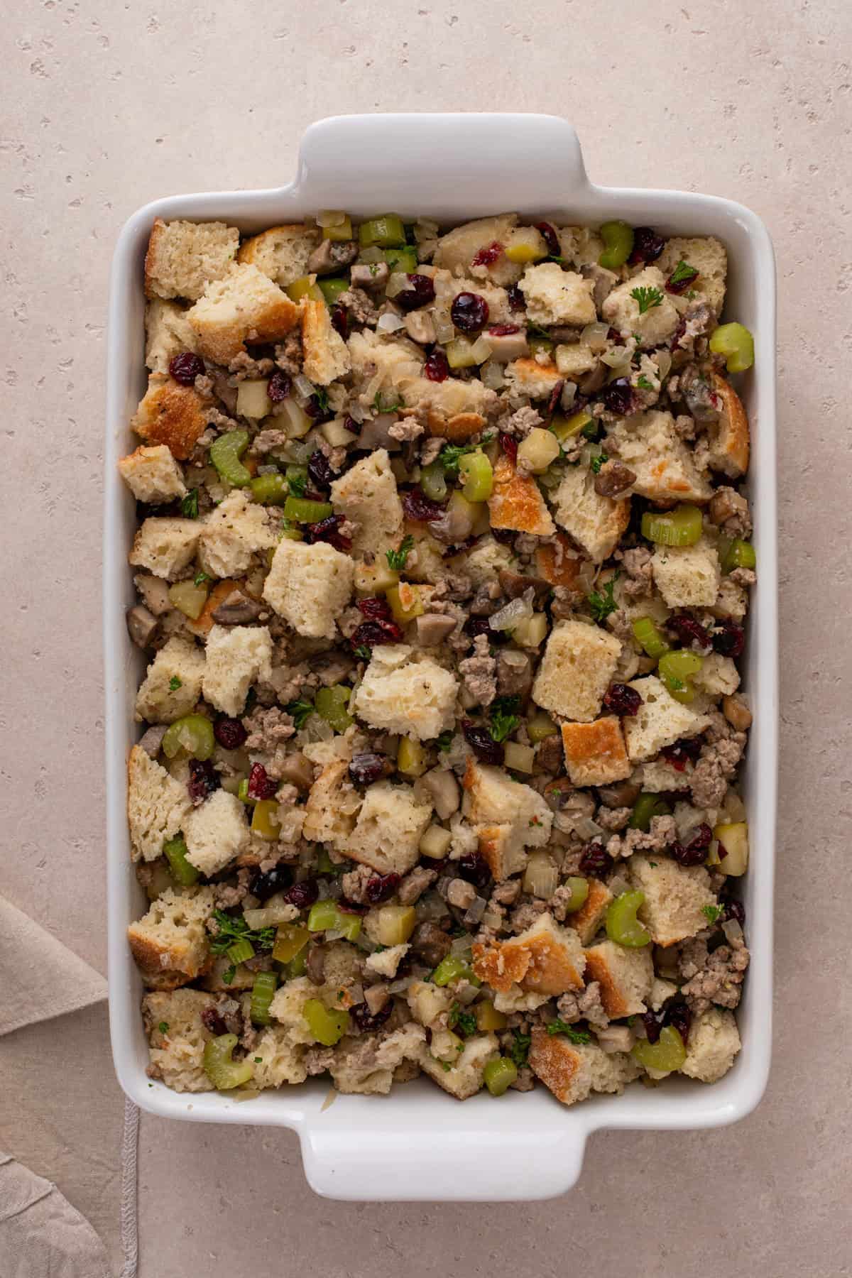 Unbaked sausage and cranberry stuffing in a baking dish, ready to go in the oven.