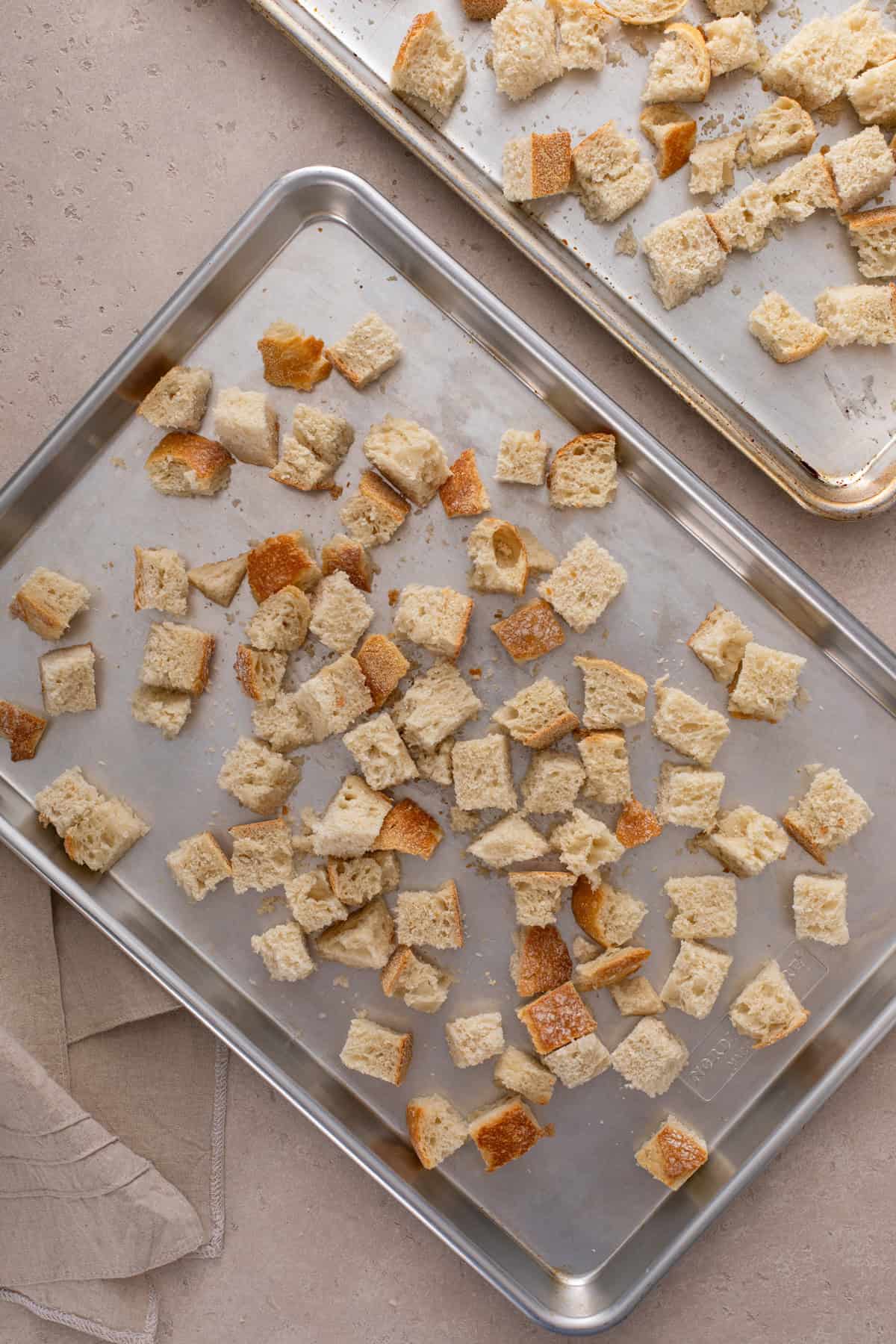 Bread cubes spread onto baking sheets.