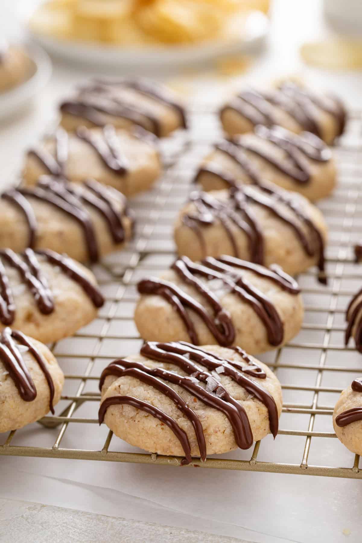 Rows of chocolate-drizzled potato chip cookies on a wire rack.