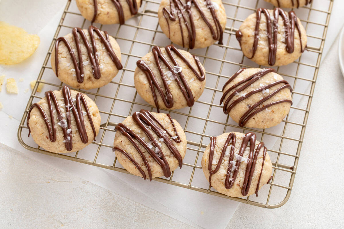 Chocolate-drizzled potato chip cookies arranged on a wire rack.