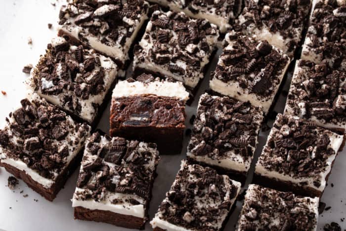Close up of sliced oreo brownies topped with vanilla frosting and chopped oreo pieces.