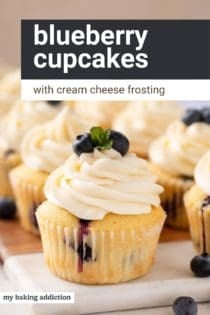 Close up of blueberry cupcakes on a marble and wooden board. Text overlay includes recipe name.