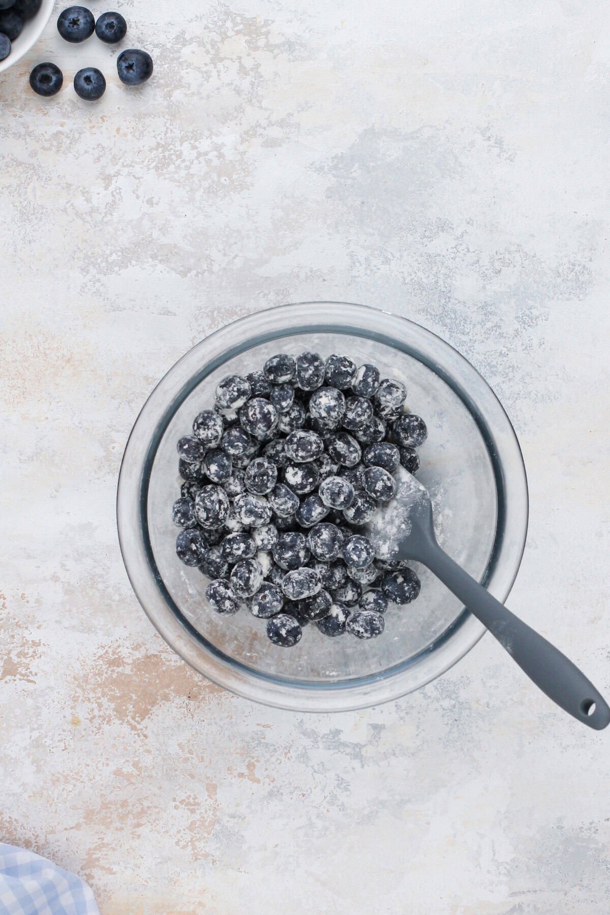 Fresh blueberries mixed with flour in a small bowl.