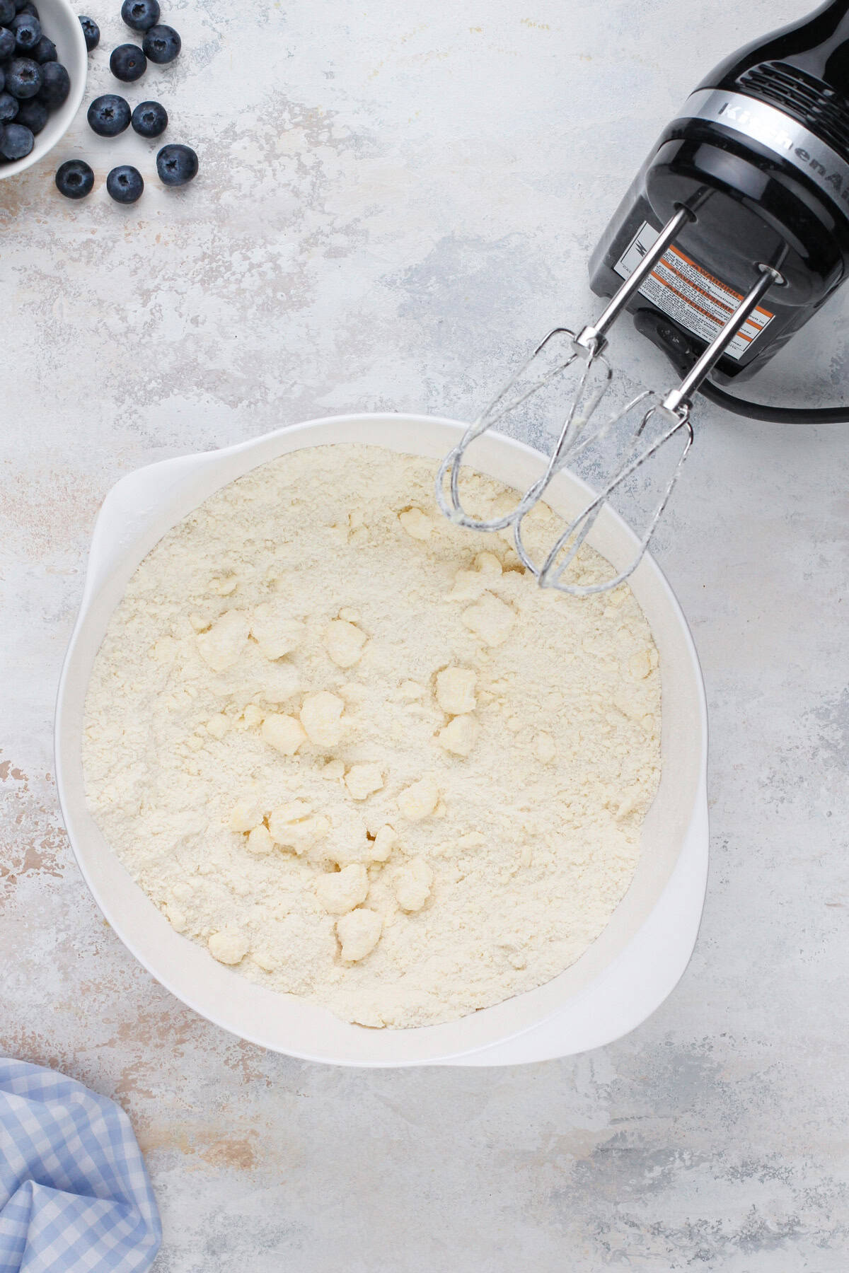 Butter mixed into dry ingredients for blueberry cupcakes in a white bowl.