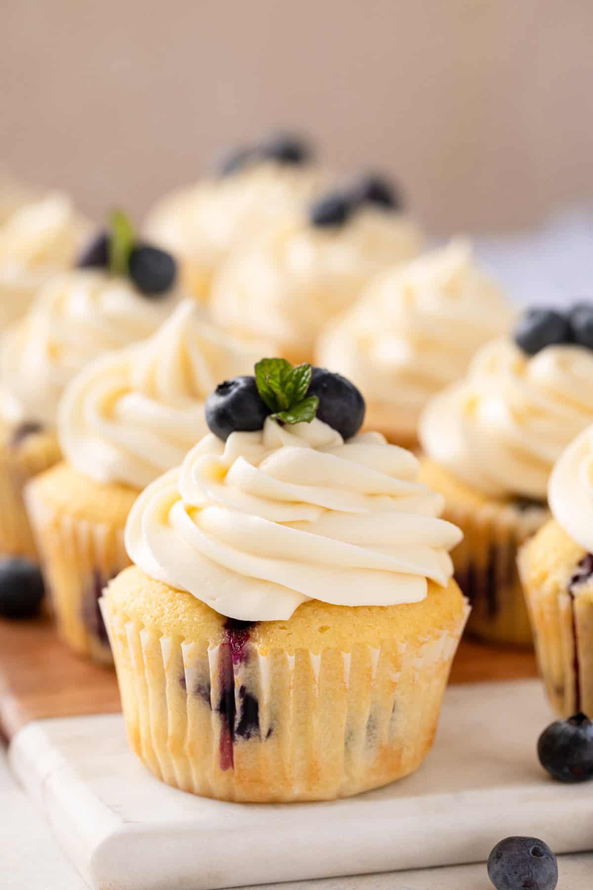 Close up of blueberry cupcakes on a marble and wooden board.