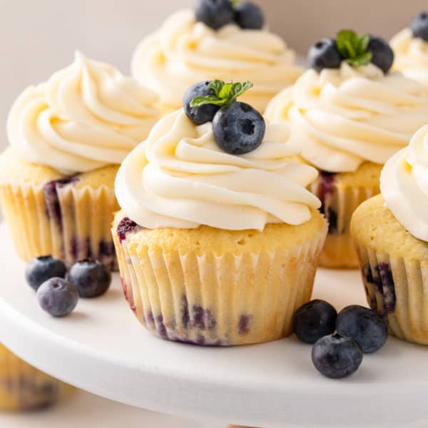 Blueberry cupcakes on a white cake plate.
