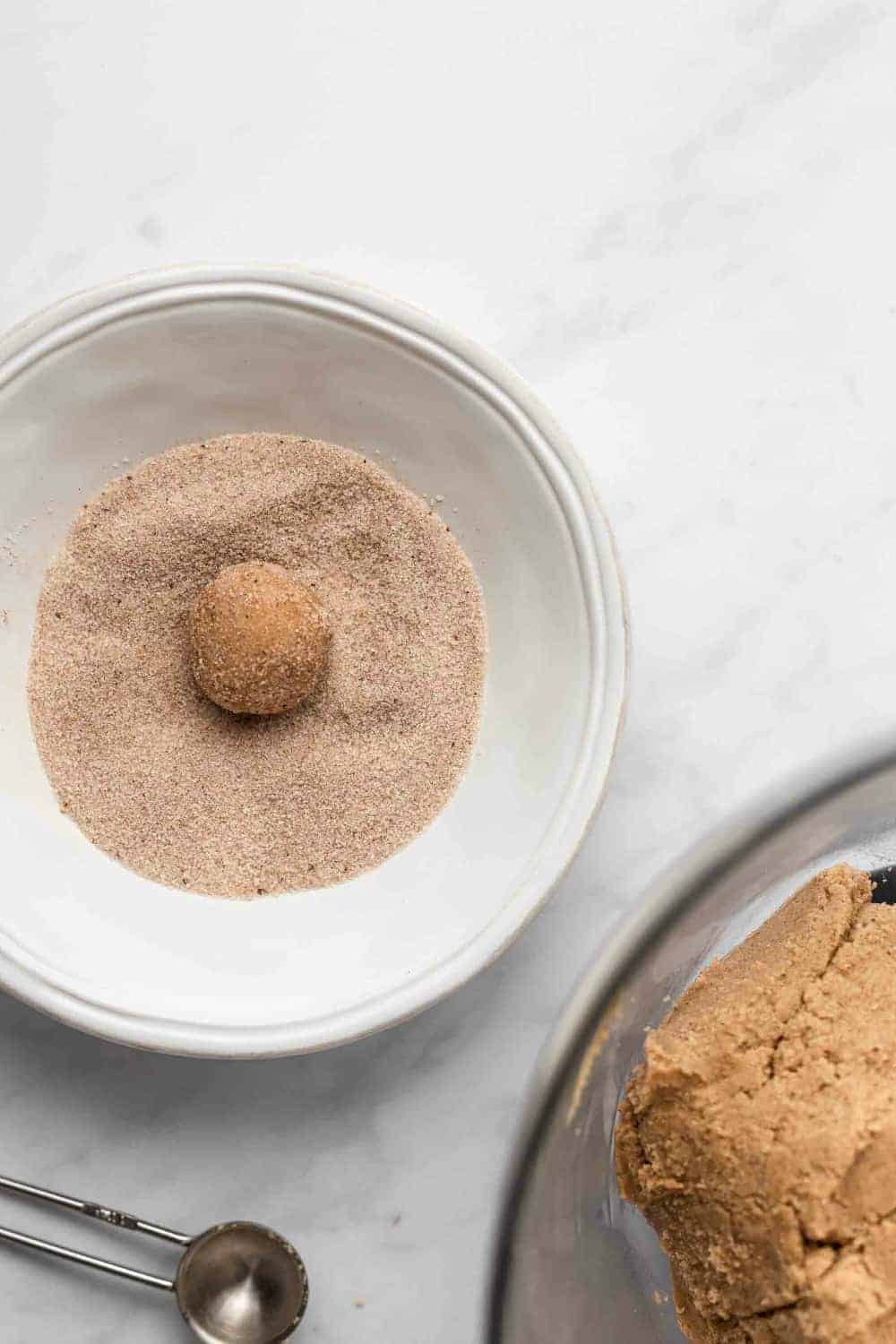 Ball of sugar cookie dough being rolled in chai spices
