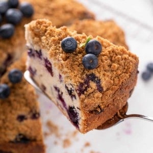 Cake server lifting up a slice of blueberry buckle.