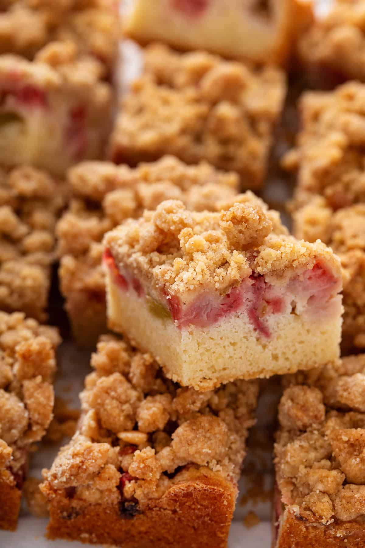 Slice of strawberry rhubarb cake stacked on other slices of the cake.