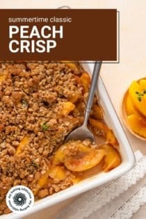 Overhead view of a spoon in the corner of a white baking dish of peach crisp. Text overlay includes recipe name.