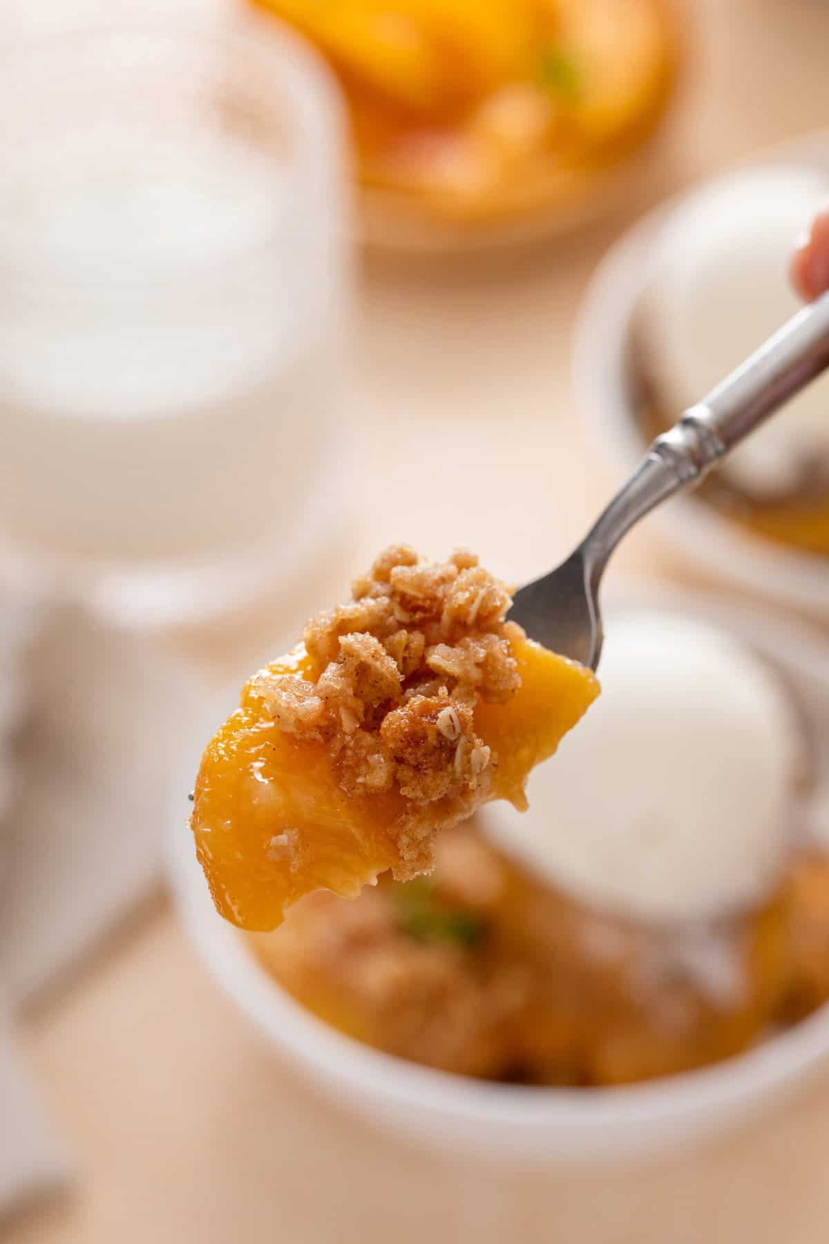 Fork holding up a bite of peach crisp to the camera.