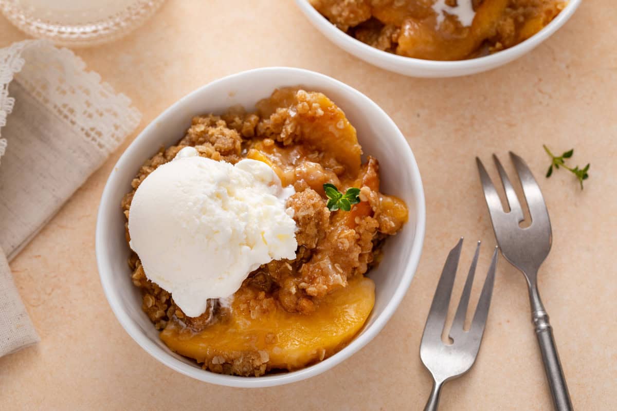 Overhead view of peach crisp a la mode in a white bowl.