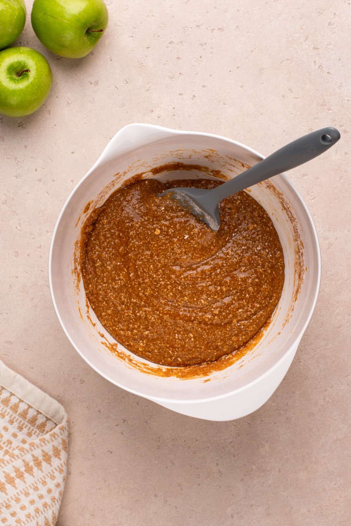 Dry and wet ingredients for apple spice cookies mixed in a white bowl.