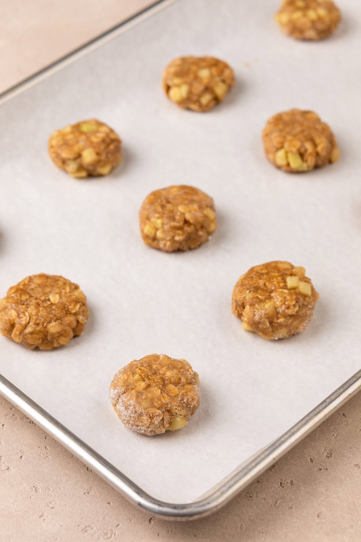 Unbaked apple spice cookies on a parchment-lined cookie sheet, ready to go in the oven.