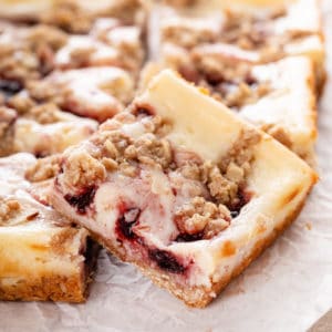 Close up of a cherry cheesecake bar on a piece of parchment paper.
