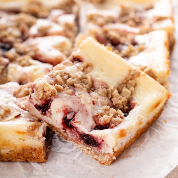 Close up of a cherry cheesecake bar on a piece of parchment paper.