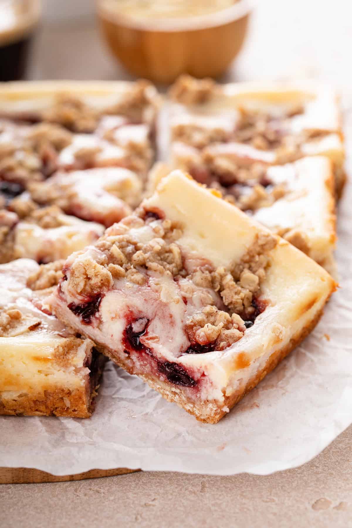 Sliced cherry cheesecake bar on a piece of parchment paper.
