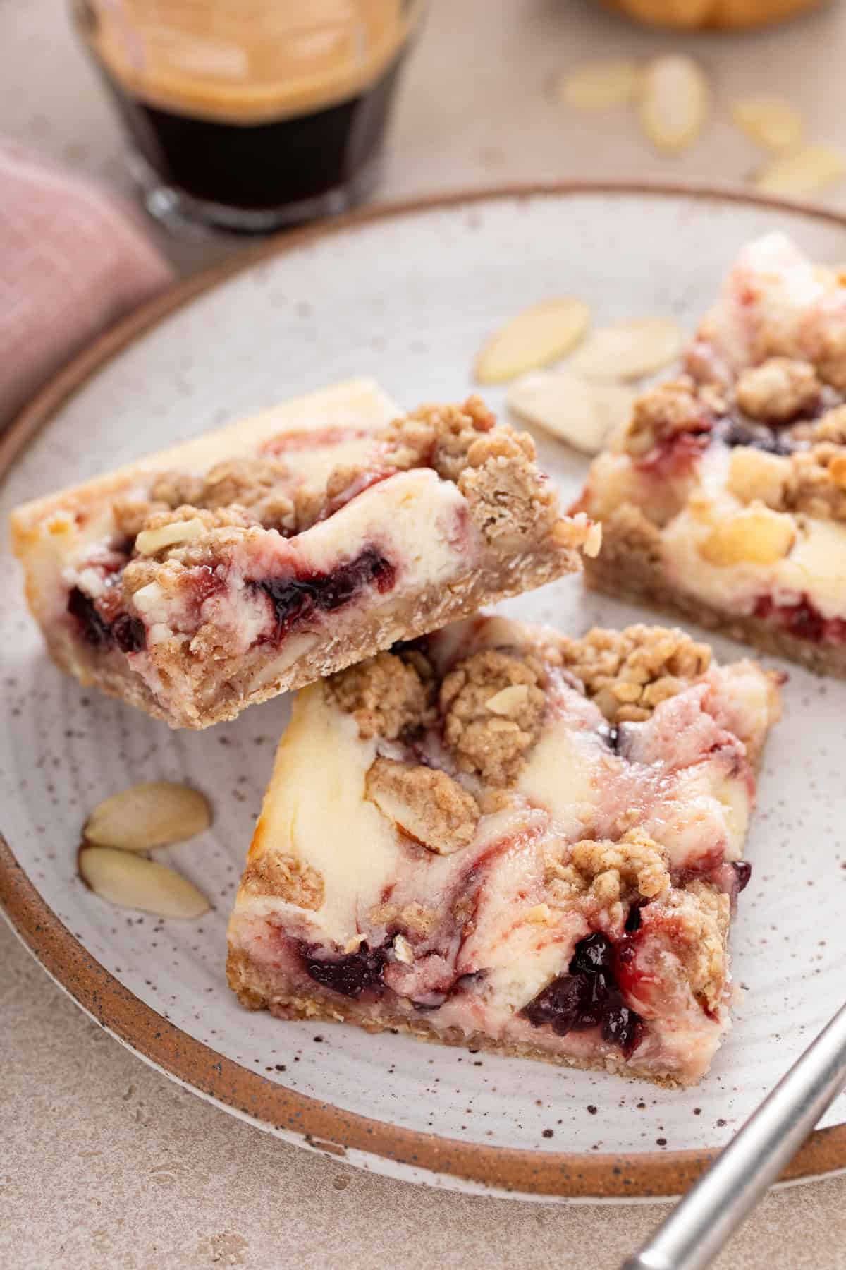 Close up of two cherry cheesecake bars on a plate.