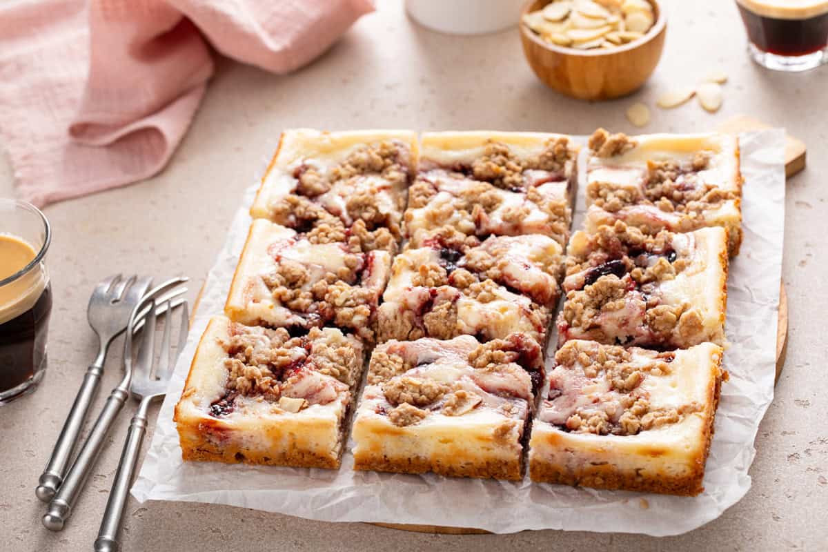Sliced pan of cherry cheesecake bars on a piece of parchment paper.