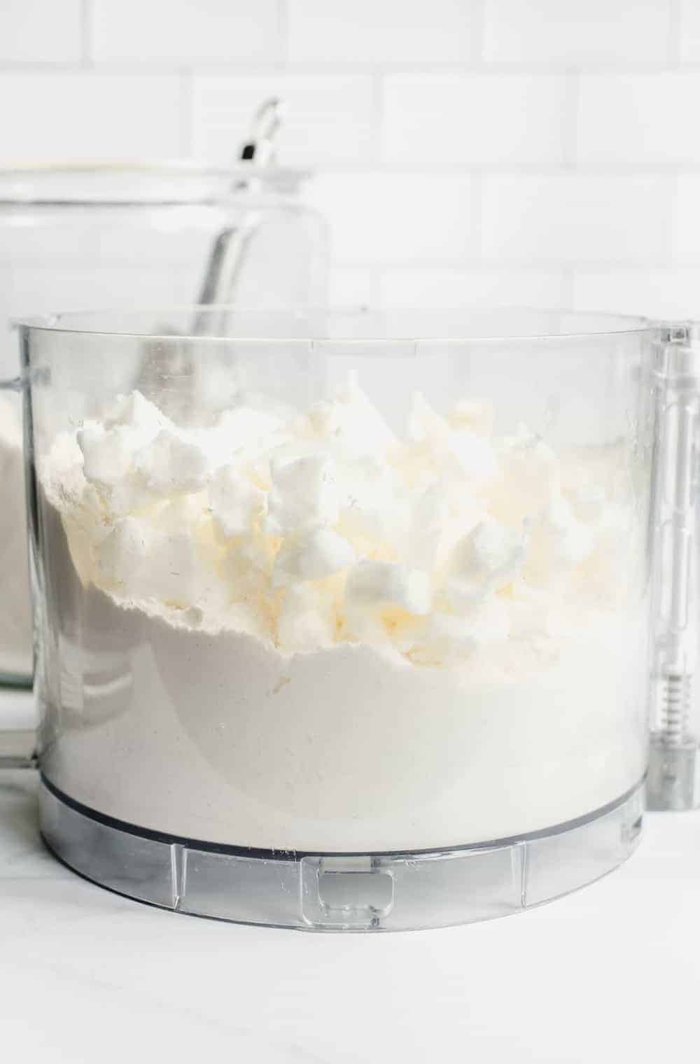 Side view of ingredients for homemade bisquick mix in the bowl of a food processor