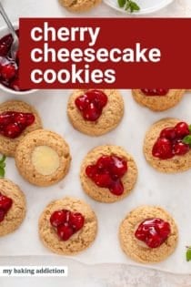 Overhead view of cherry cheesecake cookies on a marble board. Text overlay includes recipe name.