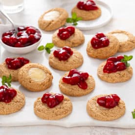 Cherry cheesecake cookies scattered on a white marble platter.