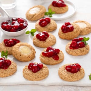 Cherry cheesecake cookies scattered on a white marble platter.