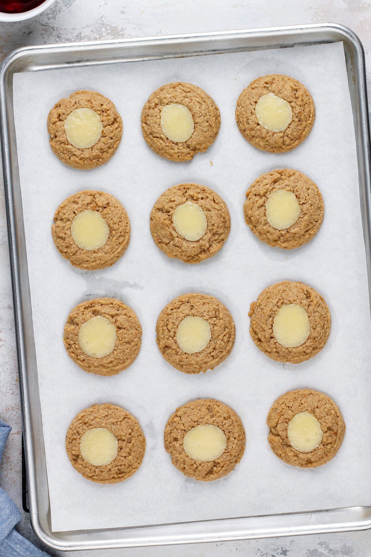 Baked cheesecake cookies cooling on a baking sheet.