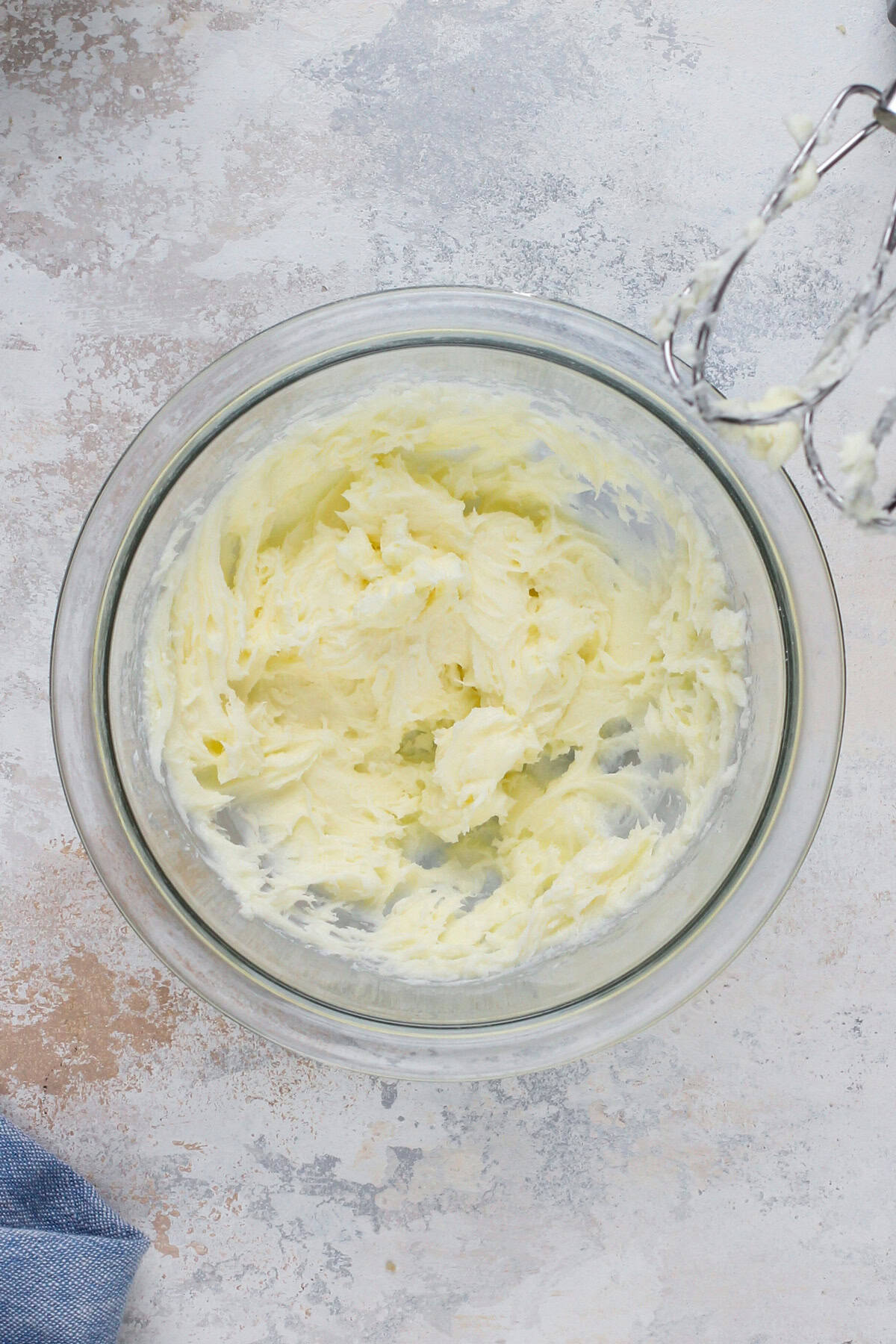 Cream cheese and sugar whipped together in a glass bowl.