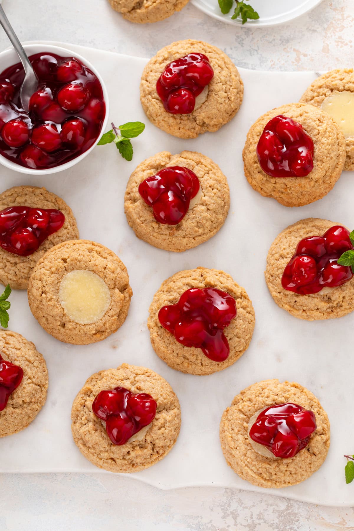 Overhead view of cherry cheesecake cookies on a marble board.