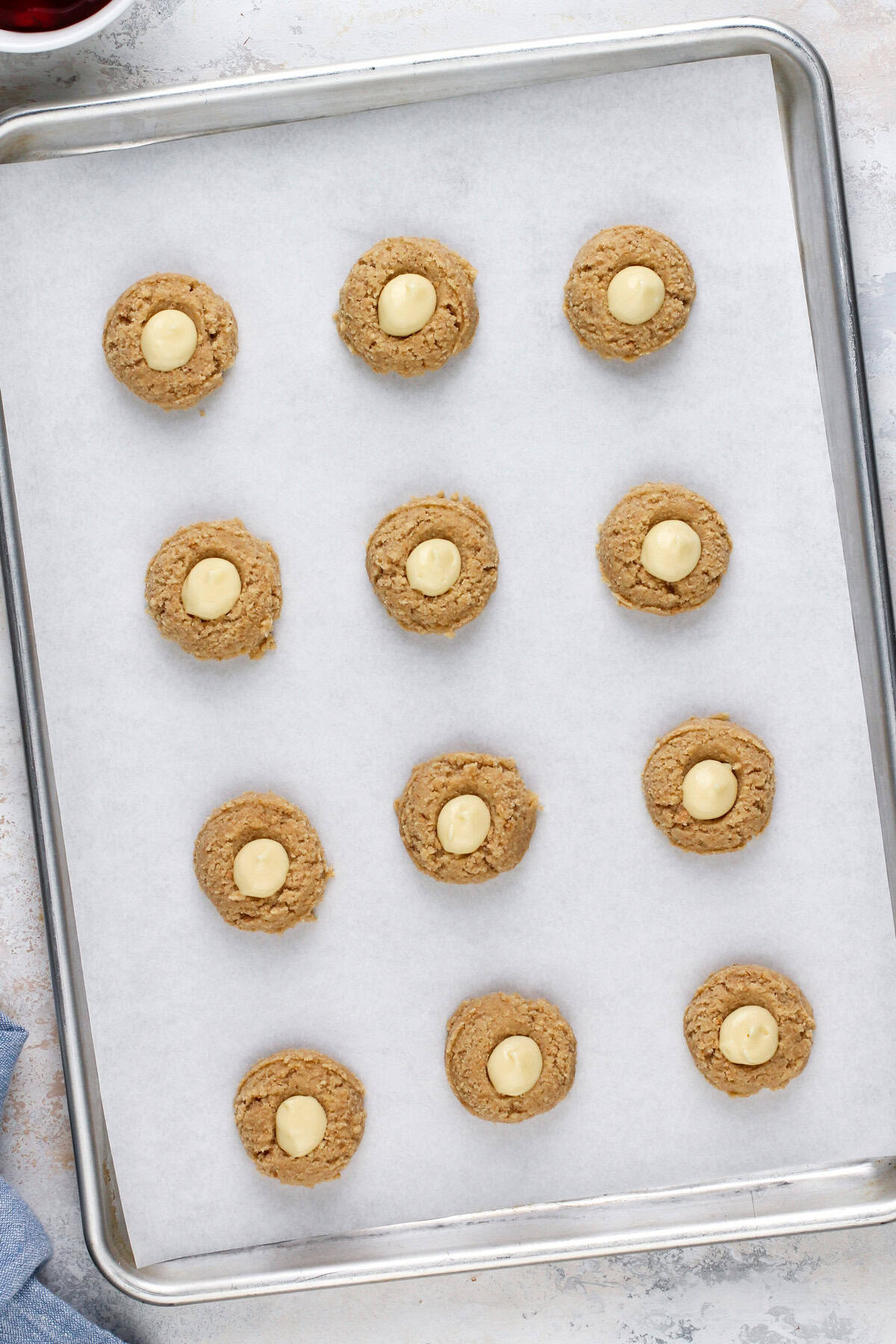 Unbaked cheesecake cookies on a parchment-lined baking sheet, ready to go in the oven.