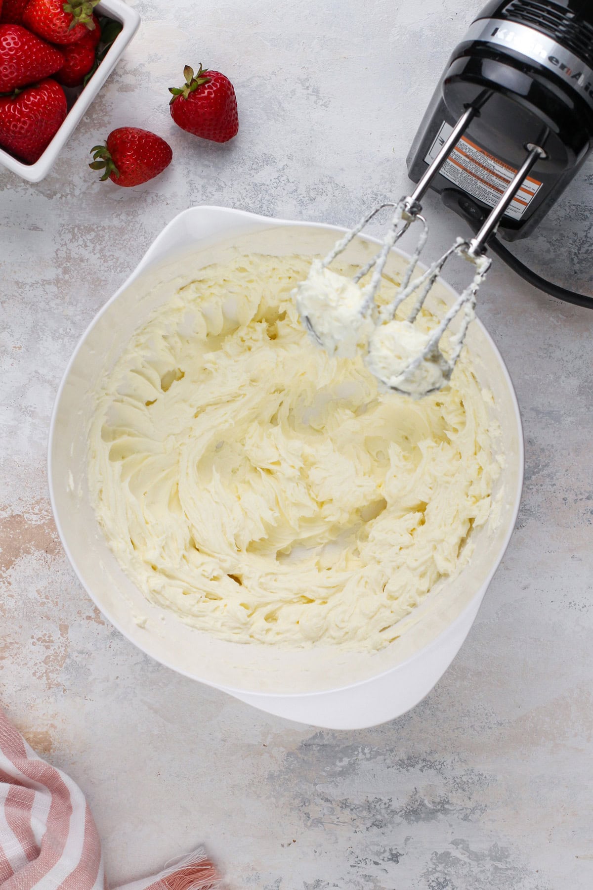 Cream cheese and sugar beaten in a white bowl.