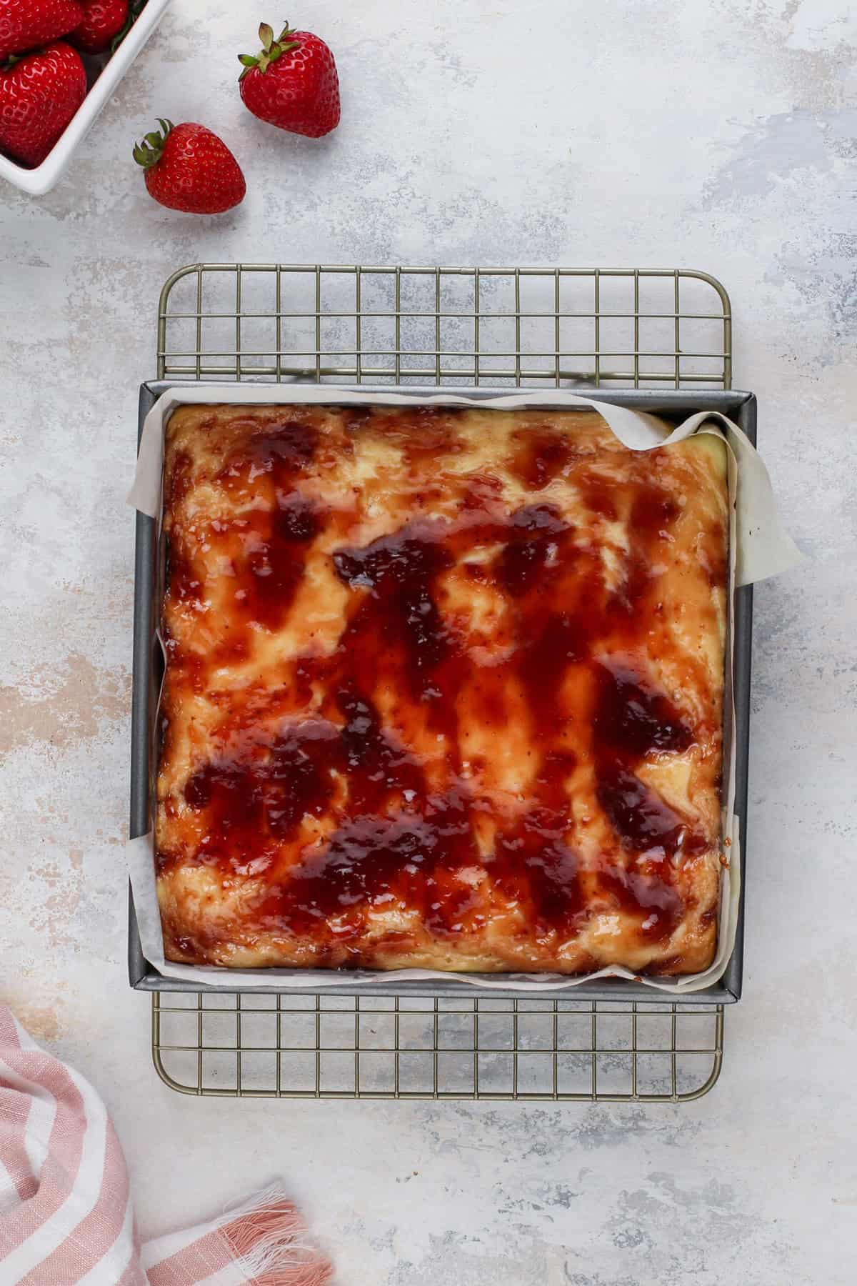 Baked and cooling strawberry cheesecake bars on a wire rack.